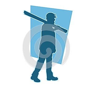 silhouette of a worker walking and shouldering wood boards.