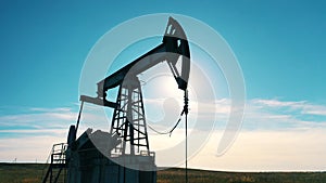 Silhouette of a working oil pump jack. Close up