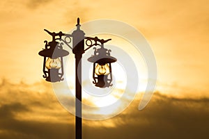Silhouette wrought iron street lamp at sunset