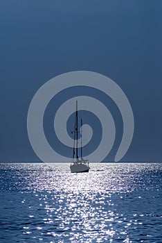 Silhouette of a yacht in the sea in the light of the Moon at night