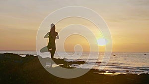 Silhouette yoga practice at sunset. Yong woman doing yoga exercise on the beach