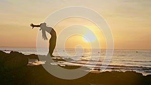 Silhouette yoga practice at sunset. Yong woman doing yoga exercise on the beach