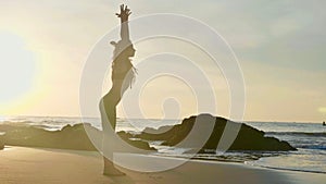 Silhouette yoga practice at sunset. Yong woman doing yoga exercise on the beach