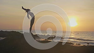 Silhouette yoga practice at sunset. Yong woman doing yoga exercise on the beach