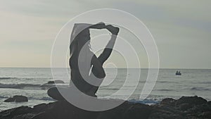 Silhouette yoga practice at sunset. Yong woman doing yoga exercise on the beach