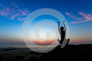 Silhouette of yoga woman doing exercises on the ocean beach