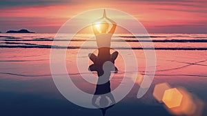 Silhouette yoga woman in Lotus pose on beach during sunset.