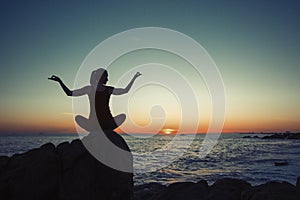 Silhouette of yoga woman meditating on the sea coast