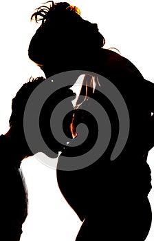 Silhouette of a yong man kissing the belly of his pregnant wife