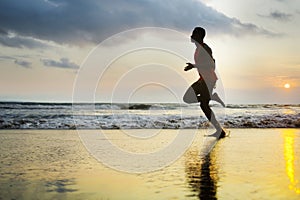 Silhouette of young attractive fit athletic and strong black afro American man running at sunset beach training hard and sprinting