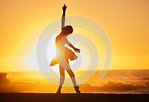 Silhouette of a young ballet dancer on the beach at sunset. Graceful slender ballerina dancing with passion and