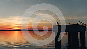 Silhouette of a young beautiful girl against the background of the sunseton the river