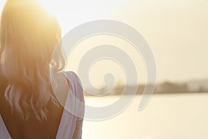 Silhouette of a young beautiful girl playing the saxophone at sunrise by the river, a woman in a long dress on the nature at