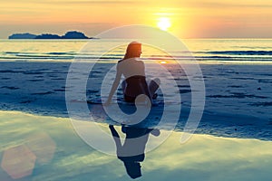Silhouette of young beautiful girl sitting on the beach