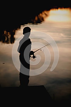 Silhouette of a young boy fishing