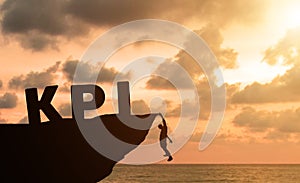 Silhouette Young businessman climbing the mountain to achieve KPI with sky, clouds and sunset background. Fight for reach key