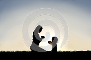 Young Mother and her Little Child are Praying Outside at Sunset on a Summer Day