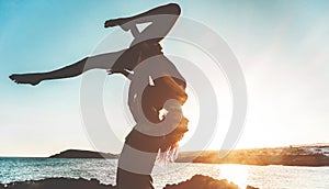 Silhouette young couple doing acroyoga outdoor on the beach - Woman and man training on evening time at sunset - Soft focus on