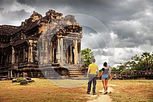 Silhouette young couple in love explores the famous ancient of Khmer architecture style temple Angkor Wat