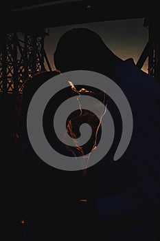 Silhouette of young couple in love that hugging on sunset amidst a bridge under construction. Man and woman standing