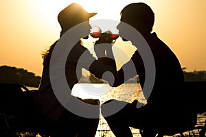 Silhouette of a young couple in love to leave on a picnic out of town drinking wine brotherhood of glass goblets