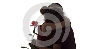 Silhouette of a young couple in love on white isolated background, man gives a woman a rose flower and woman hugging him from