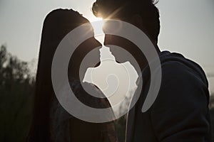 Silhouette of young couple very close to each other, sunbeam and lens flare