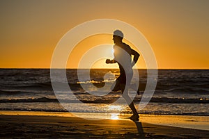 Silhouette young dynamic athlete runner man with fit strong body training on Summer sunset beach running barefoot in sport healthy