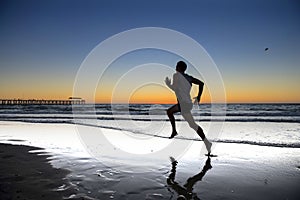 Silhouette young dynamic athlete runner man with fit strong body training on Summer sunset beach running barefoot in sport healthy