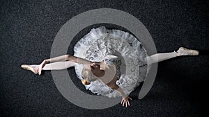 Silhouette of young elegant woman ballerina drops on splits, stretching concept, ballet concept, top shot