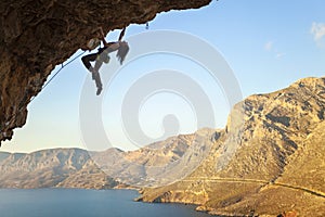 Silhouette of a young female rock climber on a cliff.