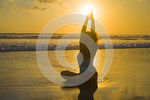 Silhouette of young fit and attractive sport woman in beach sunset yoga practice workout sitting on wet sun in front of sea in med