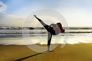 Silhouette of young fit Muslim woman covered in Islam hijab head scarf training martial arts karate kick attack and fitness