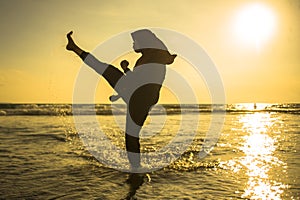Silhouette of young fit Muslim woman covered in Islam hijab head scarf training martial arts karate kick attack and fitness