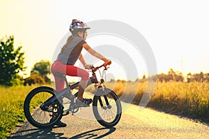 Silhouette of young girl on a bicycle at sunset