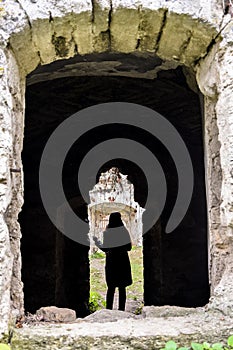 Silhouette of a young girl in the doorway of a dilapidated ancient synagogue.View through an arched window. Rashkov, Moldova.