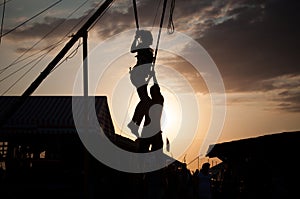 Silhouette of a young girl jumping on a bungee on a trampoline on a sunset background on a sea