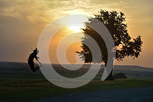 Silhouette of a young girl jumping on the meadow