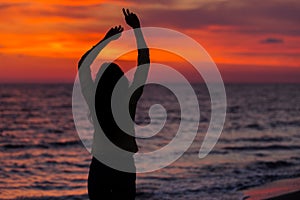 Silhouette of young girl, jumping with silk cloth against of sea sunset