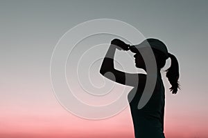 Silhouette of young girl over sunset sky background.  People, travel, nature concept.