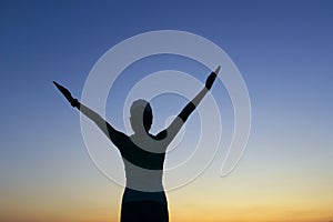 Silhouette of young girl over sunset sky background.  People, travel, nature concept.