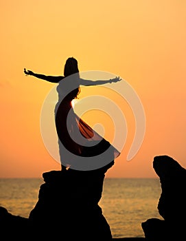 A silhouette of a young girl on rock at sunset 3 photo