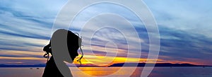 Silhouette of a young girl with sunset over the Adriatic Sea in background - Makarska