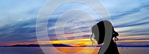 Silhouette of a young girl with sunset over the Adriatic Sea in background in Makarska, Croatia