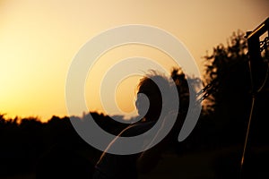 Silhouette of a young girl at sunset, swinging on a swing