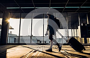 Silhouette of young girl walking with luggage walking at airport