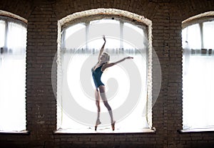 Silhouette of a young good shaped ballerina standing on the huge window. Concept of healthy lifestyle