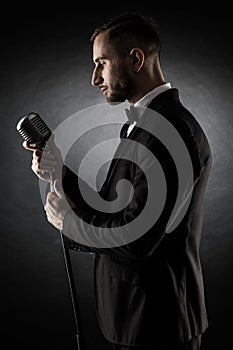 Silhouette of young handsome singer on black background.