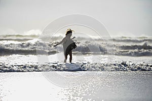 Silhouette of young happy Asian woman relaxed looking at wild sea waves on sunset tropical beach