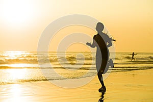 Silhouette of young happy and attractive African American runner woman exercising in running fitness workout at beautiful beach jo